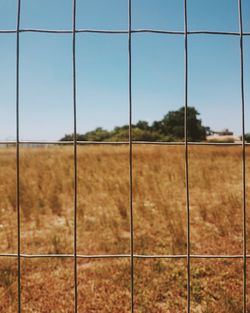 Metal grate on field against sky