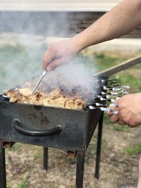 Midsection of person preparing food on barbecue grill