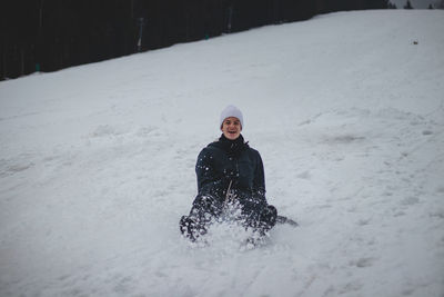 Teenager with a happy smile on his face runs down the slopes on a plastic snowboard 