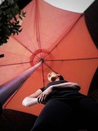 Directly below shot of woman standing by red parasol