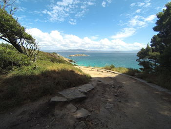 Scenic view of road by sea against sky