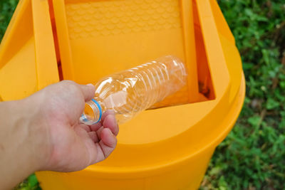 Close-up of hand throwing plastic bottle into garbage bin