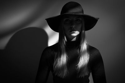 Sunlight falling on woman standing against wall