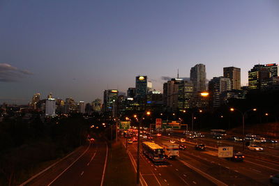 Illuminated city buildings against clear sky at night