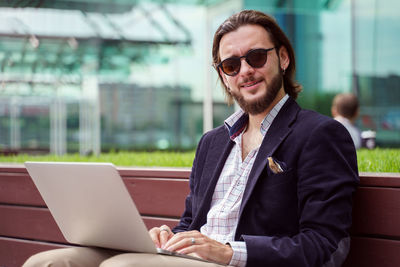 Portrait of young man using laptop while sitting in office