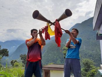 Full length of friends standing on mountain against sky