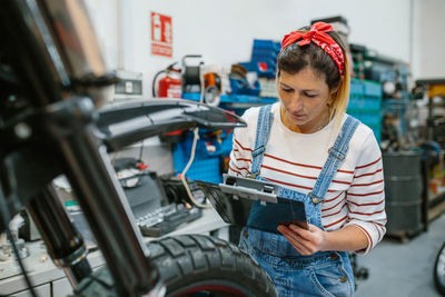 Mechanic reviewing information of motorcycle on garage