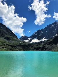 Scenic view of lake by mountains against sky