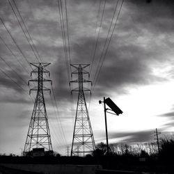 Low angle view of electricity pylon against cloudy sky