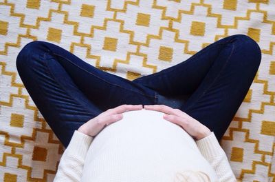 Low section of woman relaxing on tiled floor