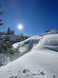 Snow covered landscape against blue sky