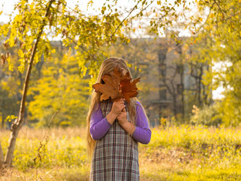 Woman holding autumn leaf on land