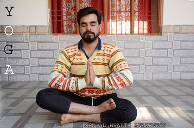 Portrait of young man sitting on wall