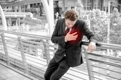 Digital composite image of businessman suffering from heart pain in elevated walkway