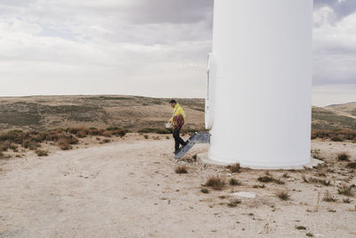 Engineer walking down from steps by wind turbine at wind farm