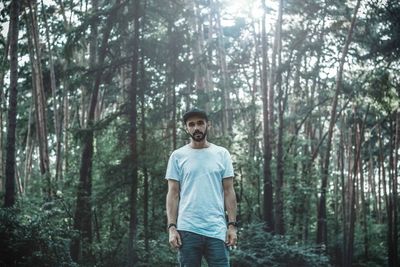 Portrait of young man standing in forest