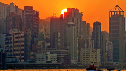 Skyscrapers in city at sunset