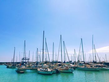 Sailboats moored in sea against clear blue sky