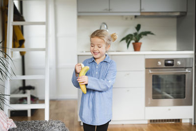 Smiling girl peeling banana