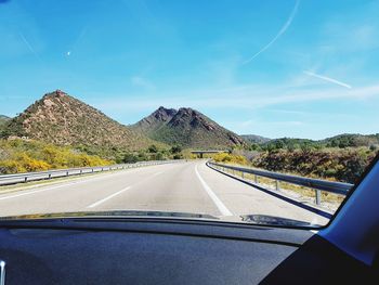 Road by mountains seen through car windshield