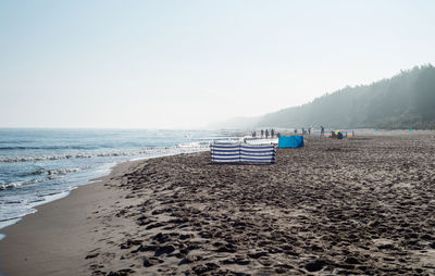 Deck chairs on beach against clear sky