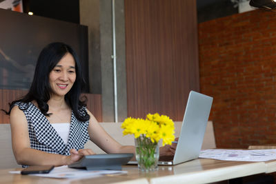 Young woman using phone while standing on table