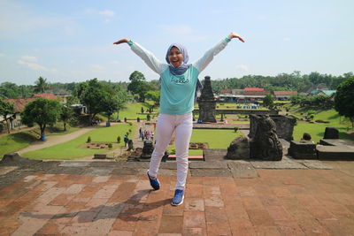 Full length of smiling young woman standing on wall