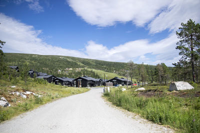 Road by buildings against sky