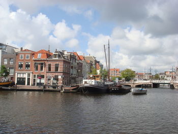 Buildings by river against sky in city