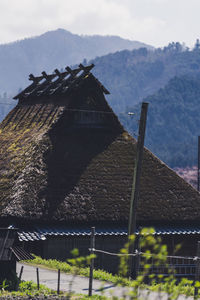 House on field by mountain against sky