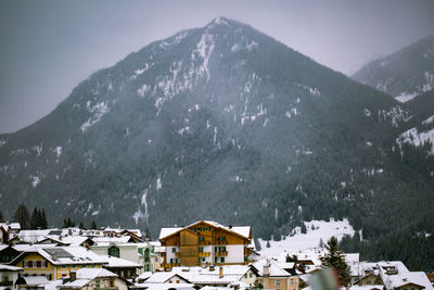 Houses by snow covered mountains against sky