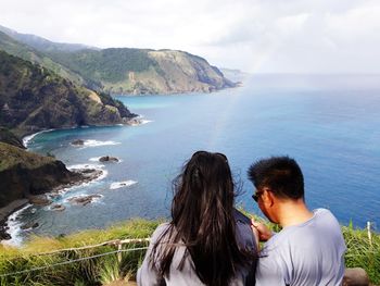 Rear view of couple looking at sea shore against sky