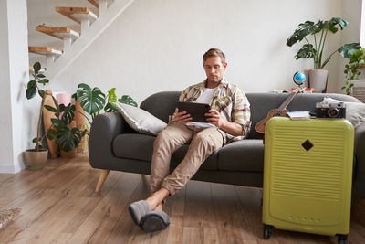 Low angle view of woman using laptop while sitting on sofa at home