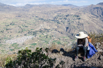 Woman using mobile phone while sitting on mountain