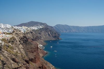 Scenic view of sea and mountains against clear blue sky