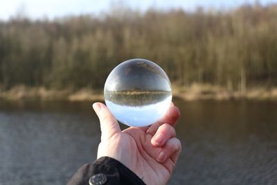 Person holding crystal ball with reflection in water