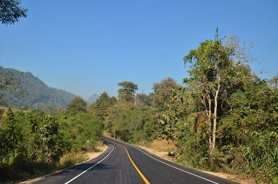 Road amidst trees against clear sky