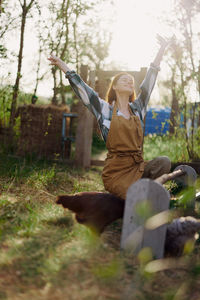 Carefree woman with arms raised sitting in farm