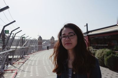 Portrait of young woman standing against sky