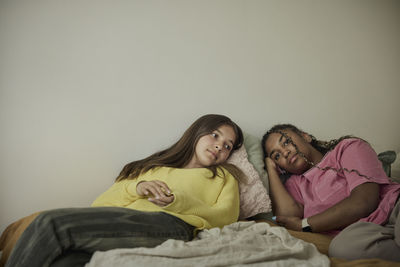 Multiracial female teenagers relaxing on bed in bedroom at home