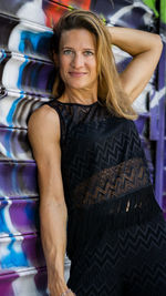 Portrait of confident mature woman standing against shutter