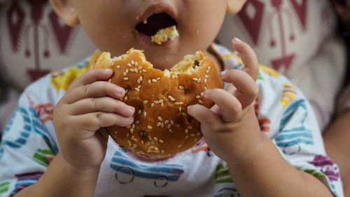 Close-up of baby eating hamburger