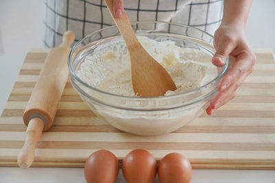 Woman kneads with a wooden spoon in a bowl at home, close-up