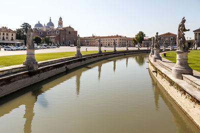 Bridge over river amidst buildings in city against sky