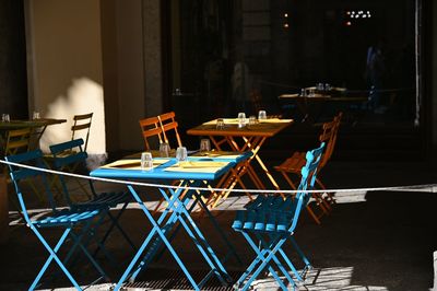 Empty chairs and tables at sidewalk cafe