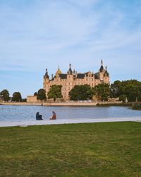 Two people sitting by the lake and watching the castle