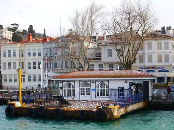 Boats in canal by buildings in city against sky