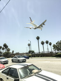 Airplane flying over road against sky