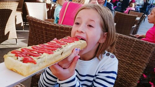 Girl eating large sandwich at restaurant