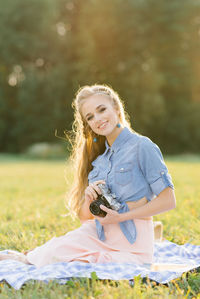 Young european tourist smiles happily using vintage camera in nature